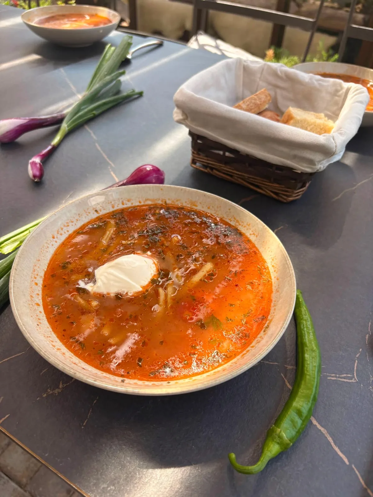 Ciorbă servită la terasa Bungard Gastro Local, cu pâine și ceapă verde