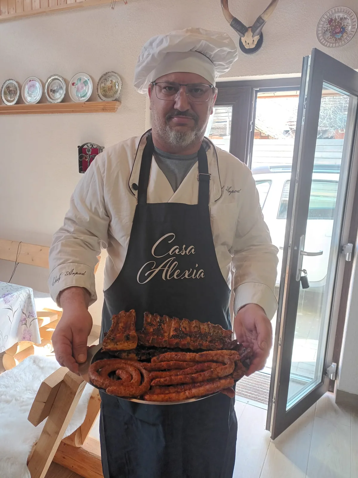Gazda Casa Alexia cu un platou de cârnați la grătar