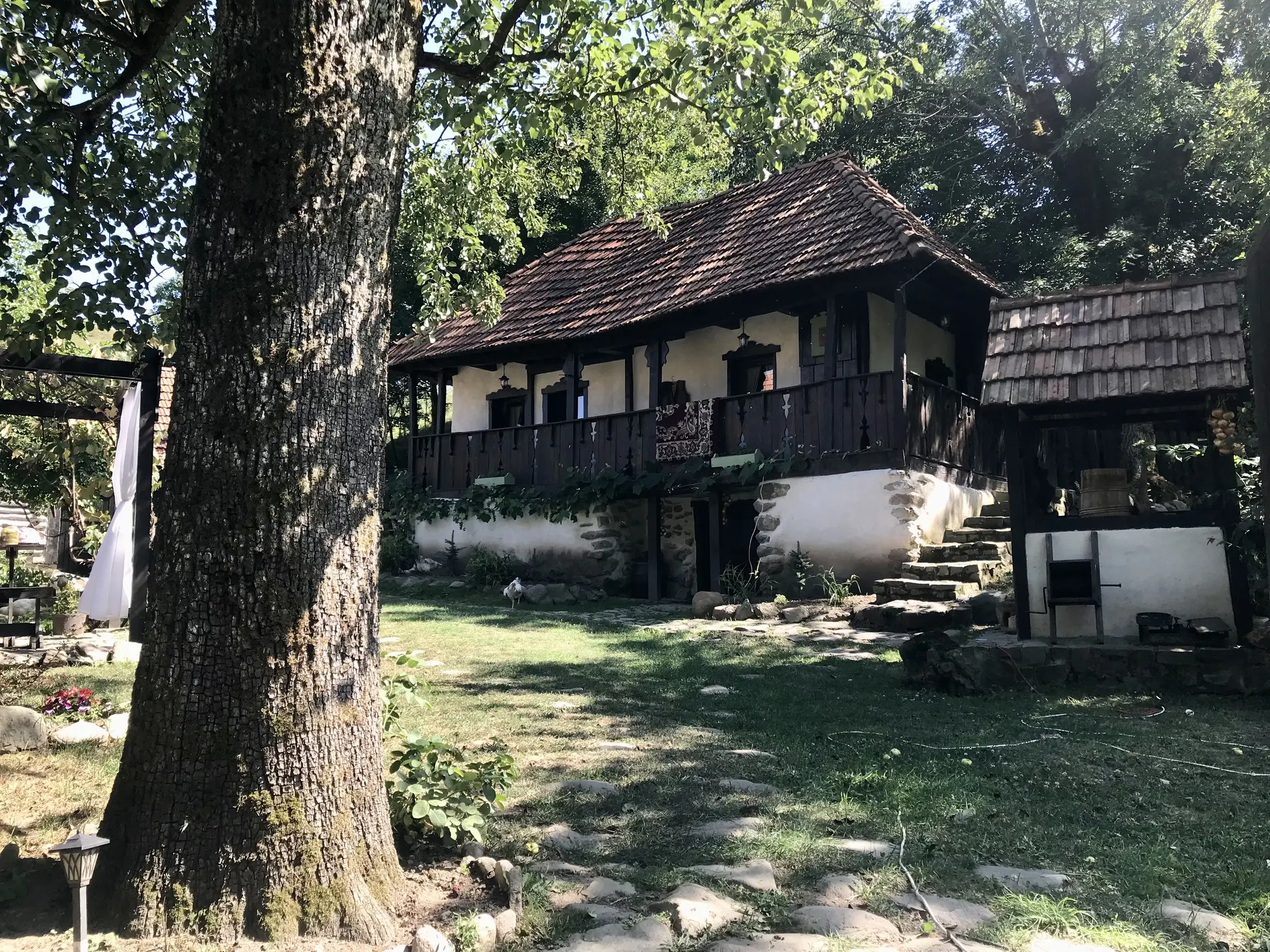 Gospodăria veche Casa Veche Voia, cu prispă din lemn și curte umbrită