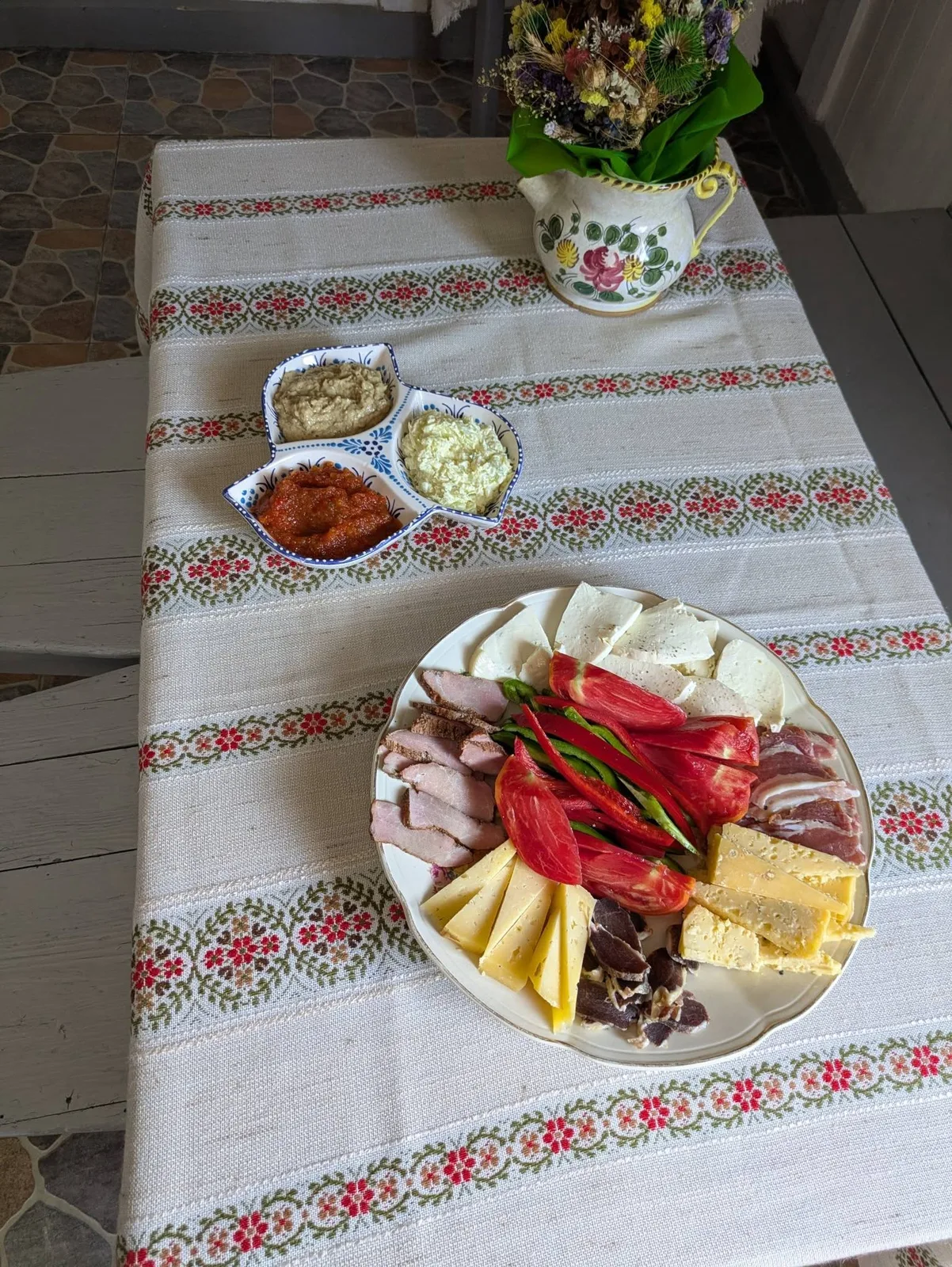 Platou rece cu brânzeturi, mezeluri și legume servit pe ștergar țesut