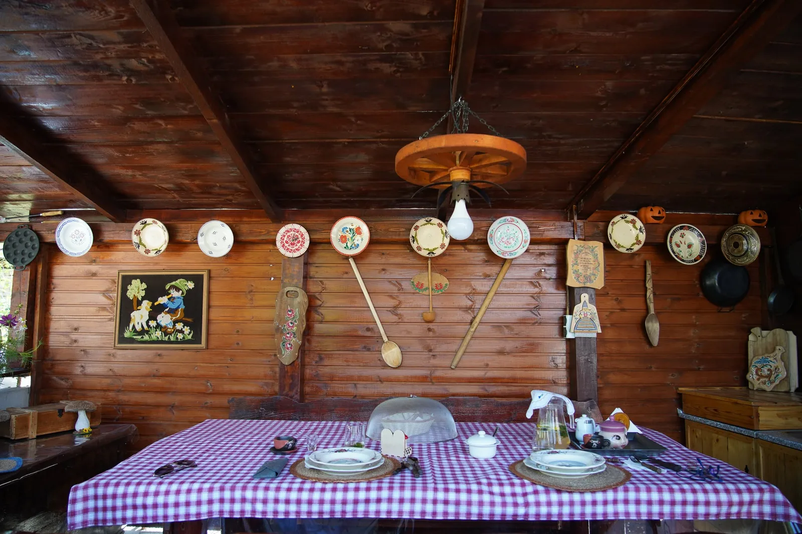 Terasa din lemn decorată cu blide pictate și pregătită pentru oaspeți