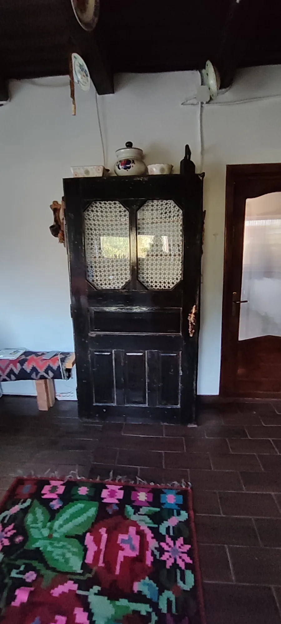 Ladă veche și covor înflorat în interiorul casei