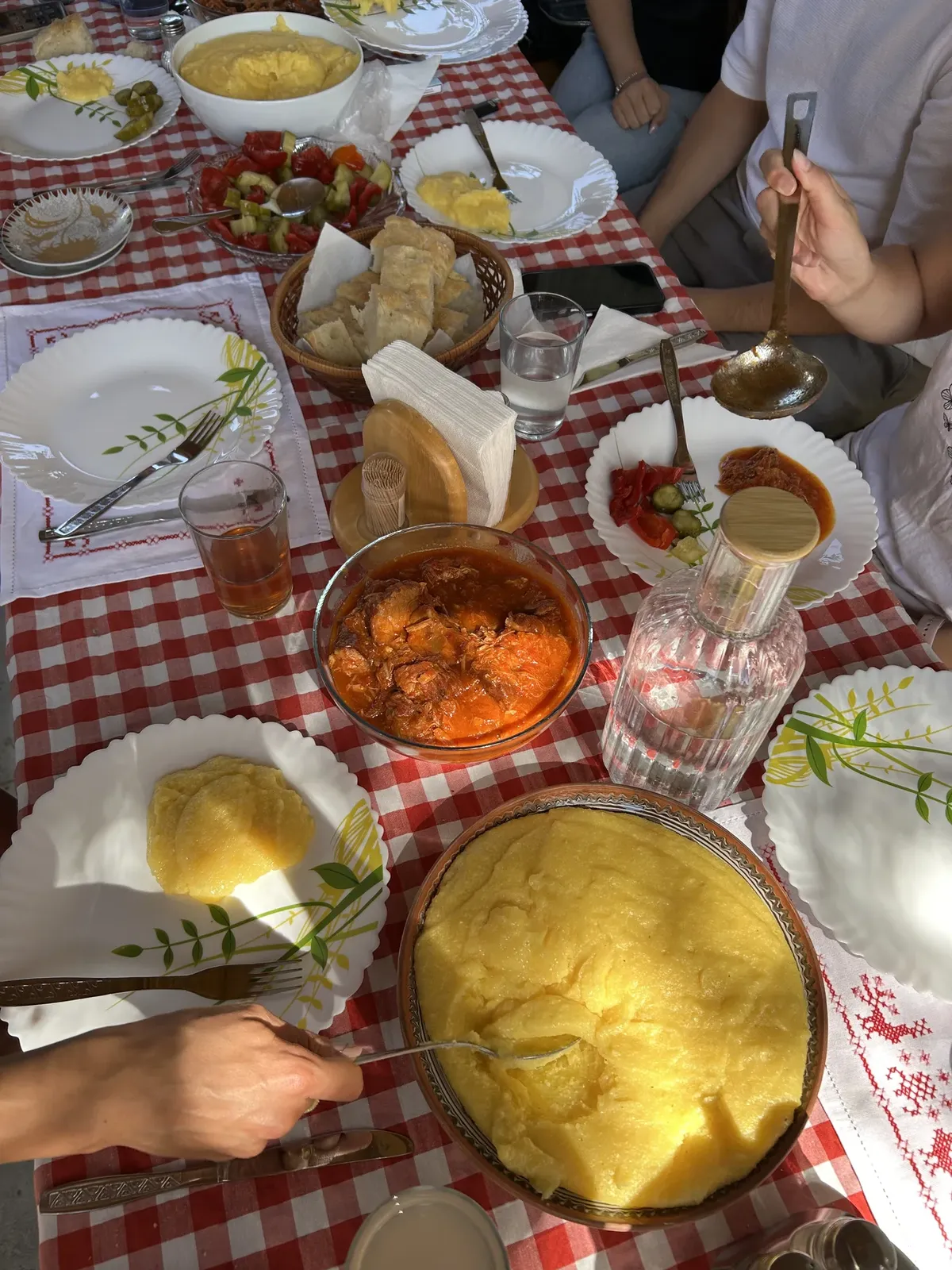 Oaspeți în jurul unei mese de vară cu mămăligă și mâncare gătită