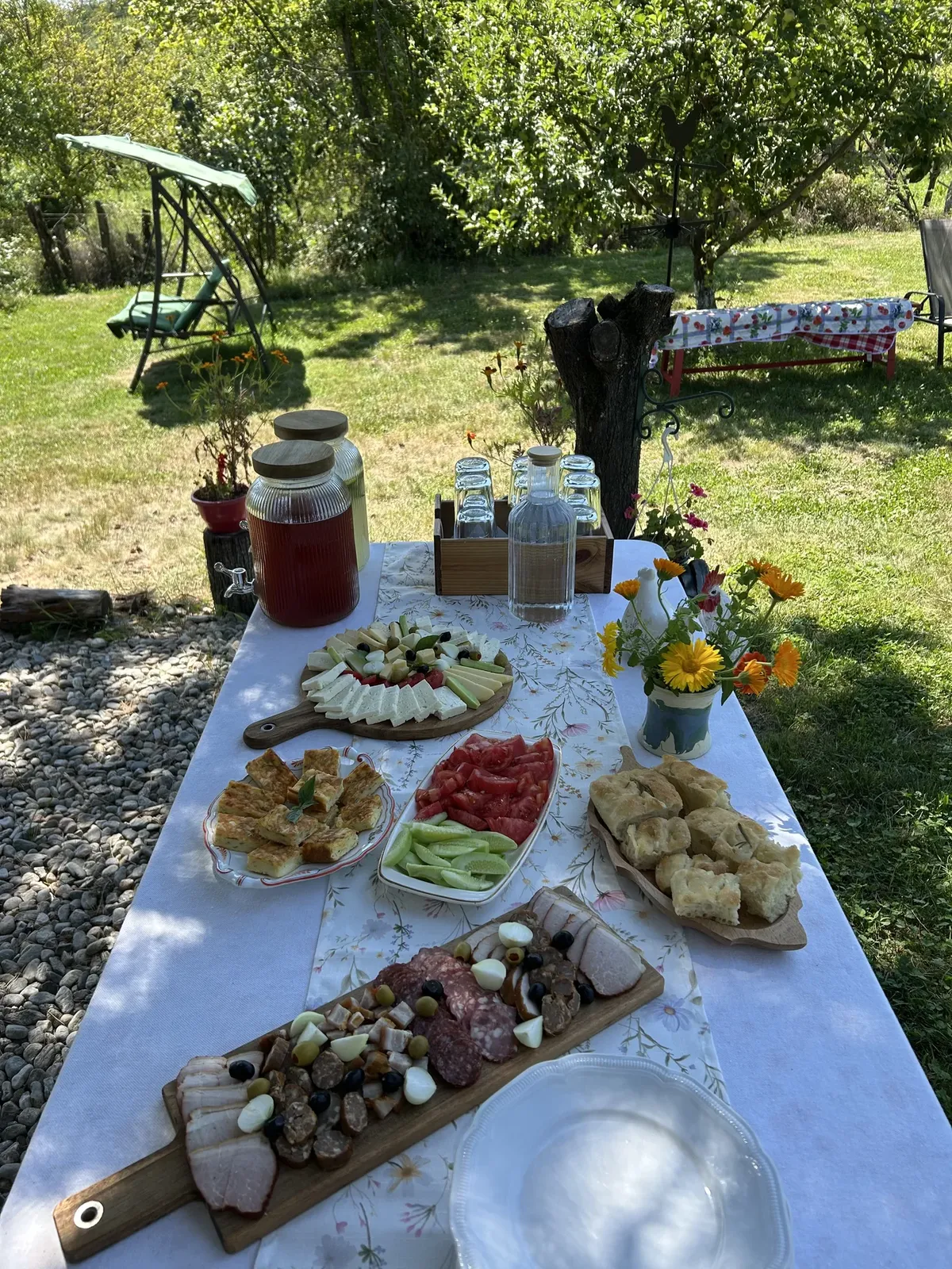 Masă cu preparate locale, întinsă în grădina La Cocoș în Deal